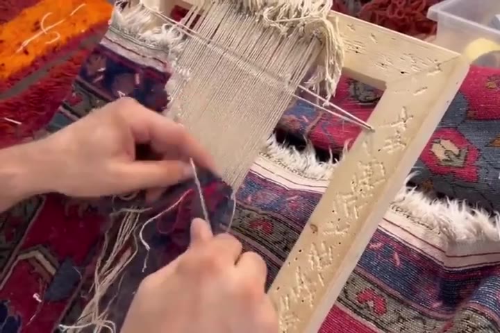 La tête du tapis bloquée sur sa règle : la frange se renoue brin par brin, la chaîne reste tendue.